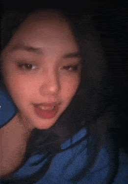 a close up of a woman 's face with a blue blanket in the background .