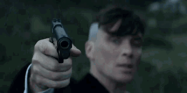 a man with a shaved head is holding a gun to his forehead .
