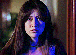 a woman with long hair and blue eyes is standing in front of a mirror .