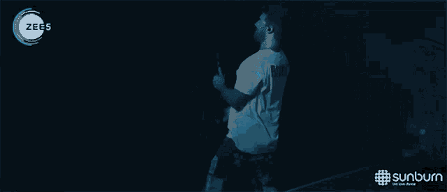 a man singing into a microphone in front of a sunburn advertisement