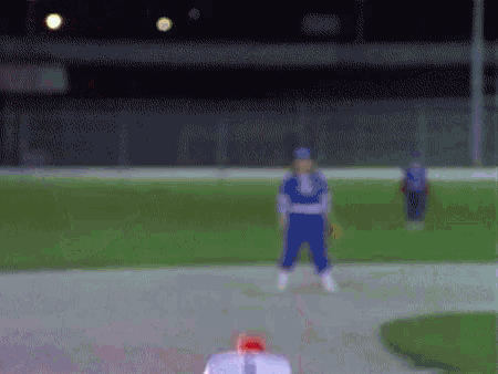 a blurry picture of a baseball field with a player wearing a blue uniform