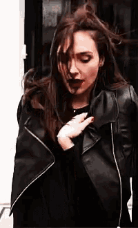 a woman is wearing a black leather jacket and a black shirt .