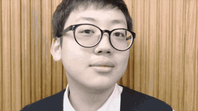 a boy wearing glasses and a white shirt looks at the camera