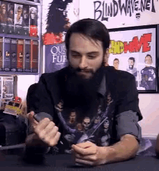 a man with a beard is sitting in front of a blindwave.net poster