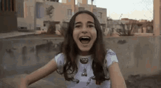 a young girl is screaming with her mouth open while sitting on a skateboard .