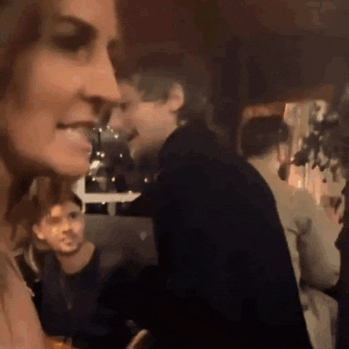 a woman is smiling while standing in a crowd of people .