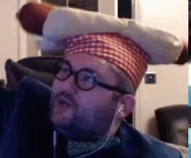a man wearing glasses and a chef 's hat with a hot dog on his head .