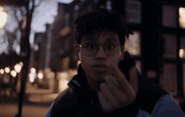 a young man wearing glasses is making a face