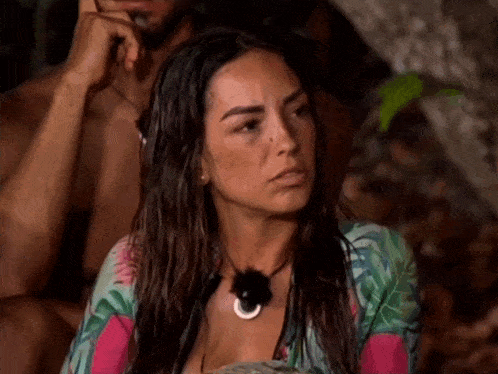 a woman is sitting next to a man in a jungle and looking at the camera .