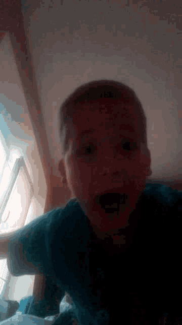 a young boy is making a funny face with his mouth open .