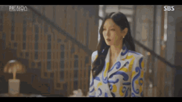 a woman is standing in front of a staircase wearing a colorful suit .