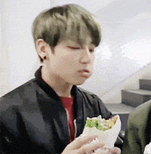 a young man is eating a sandwich with his mouth open