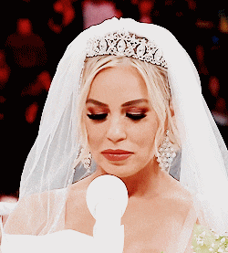 a bride wearing a veil and tiara looks down