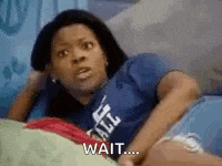 a woman in a blue shirt is laying on a bed and waiting .