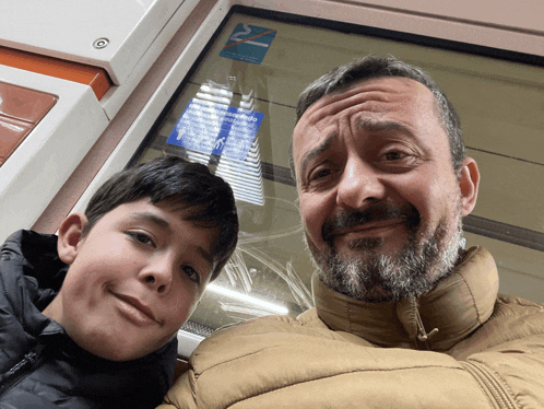 a man and a boy are posing for a picture in front of a window that has a sticker on it that says " 22 "