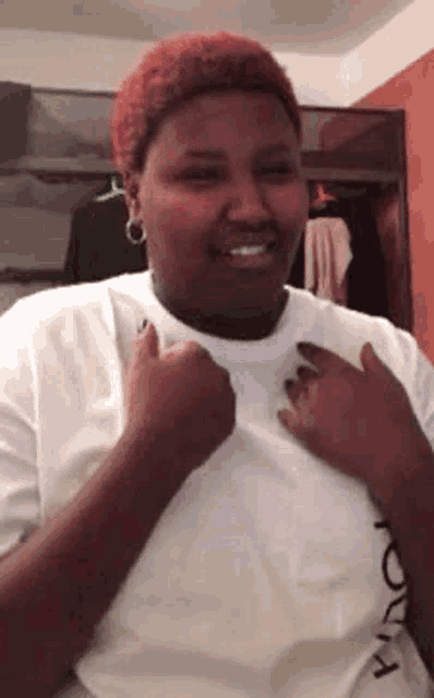 a woman with red hair is wearing a white shirt and giving a thumbs up .
