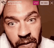 a close up of a man 's face with a beard and a live button