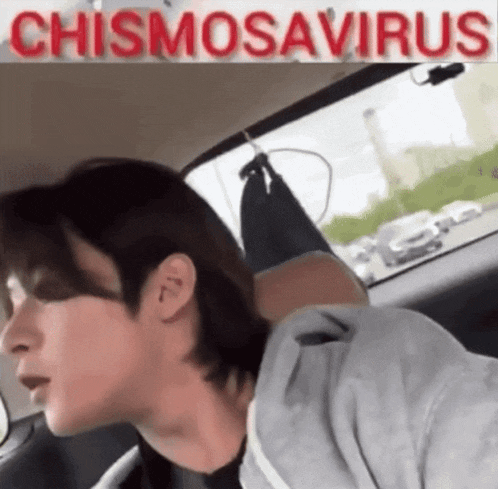 a man is sitting in a car with a sign that says chismosaurus above him
