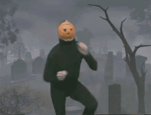 a man with a pumpkin on his head is standing in a cemetery