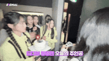 a group of girls are standing around a cake with a sign that says signal on it