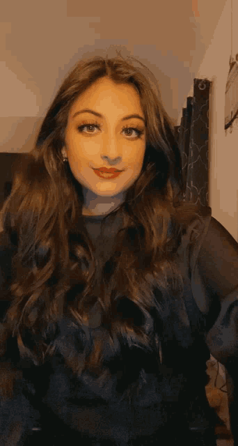 a woman with long dark hair is wearing a black top