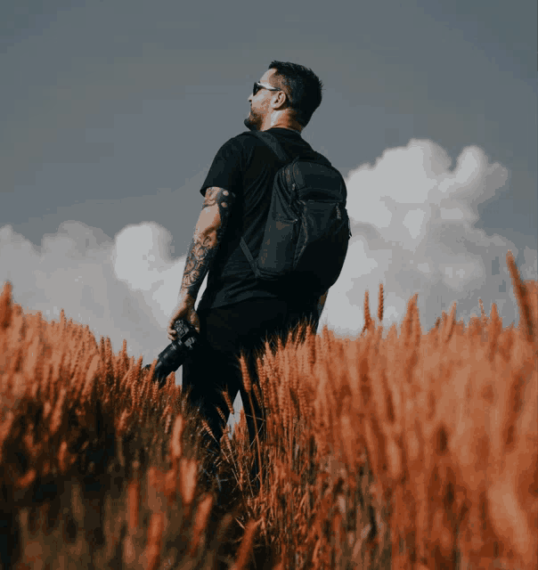 a man with a backpack stands in a field