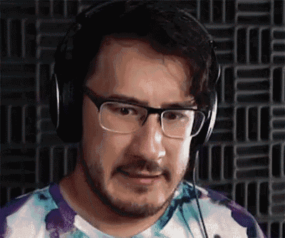 a man with a beard and glasses is wearing headphones and a tie dye shirt .