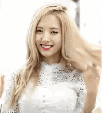 a woman with long blonde hair and red lips is wearing a white lace top .