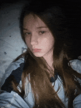 a girl with long hair is laying on a bed and looking at the camera