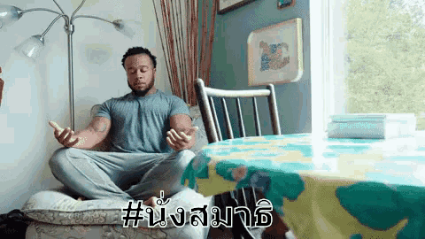 a man sits in a lotus position in front of a table with a table cloth that says # nsm