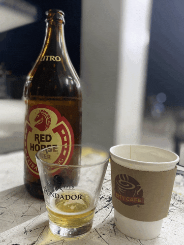 a bottle of red horse beer sits next to a cup that says city cafe