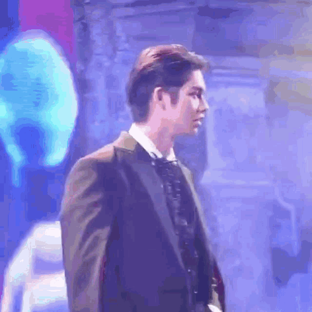 a man in a suit and tie is standing in front of a purple background .