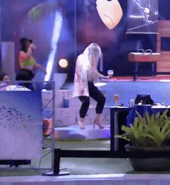 a woman is standing on a stage holding a glass