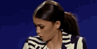 a woman wearing a striped jacket is making a funny face .