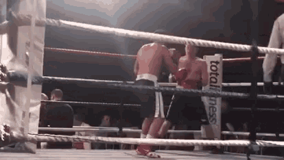 two men are boxing in a ring with a total fitness sign in the corner .