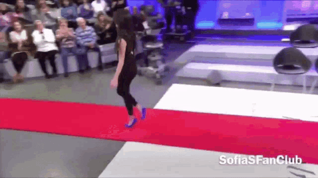 a woman walking down a red carpet with the words sofiasfanclub on the bottom right