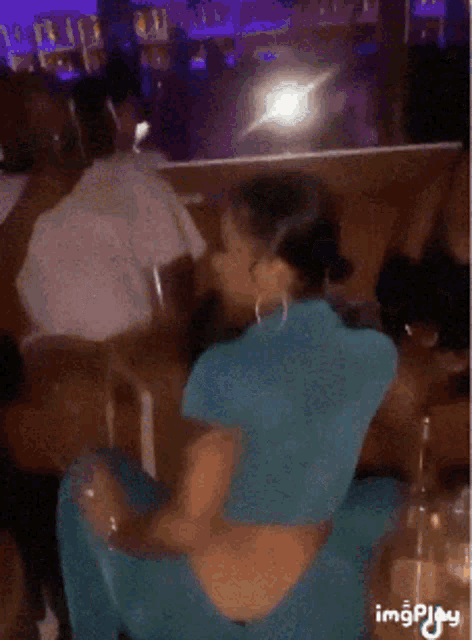a woman in a blue dress is sitting on a table with a bottle of water in front of her .