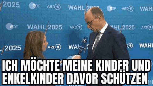 a man in a suit and tie is being interviewed by a woman in front of a blue wall .