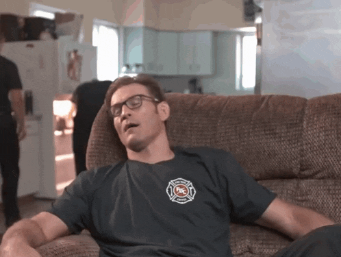 a man sitting on a couch wearing a shirt that says fire on it