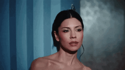 a naked woman is standing in front of a blue wall .