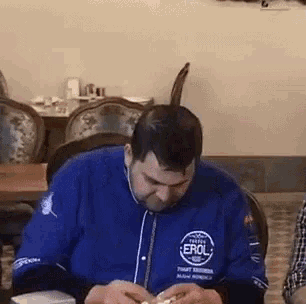 a man wearing a blue shirt that says erol is sitting at a table