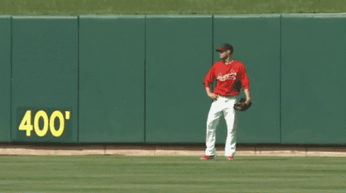 a baseball player stands on a field in front of a wall that says 400 '