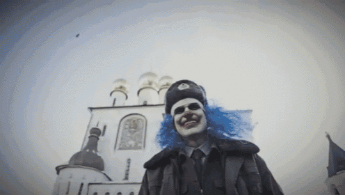 a man dressed as a clown in front of a building