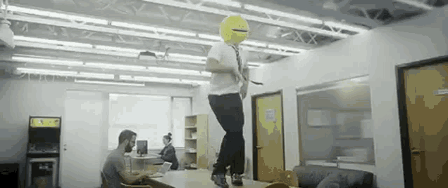 a man wearing a smiley face mask is standing on top of a table .