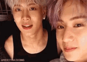 two young men are posing for a picture together . one of the men has purple hair .