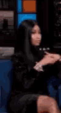 a blurry picture of a woman in a black dress sitting in a chair .