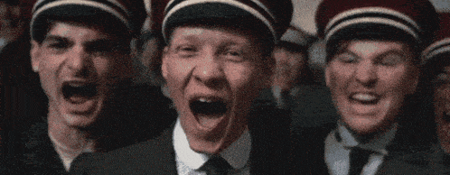 a group of men wearing suits and hats are laughing and screaming .
