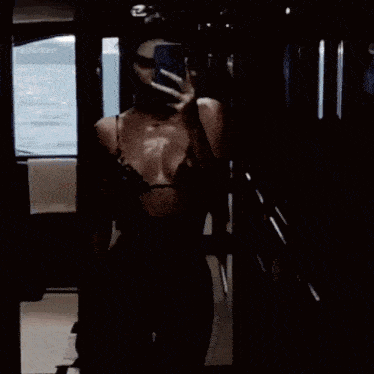 a woman is taking a picture of herself in a mirror with her phone .