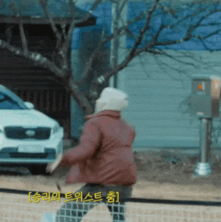 a man in a red jacket is playing tennis in front of a white kia car