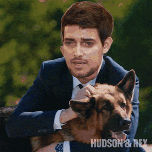 a man in a suit is petting a german shepherd with the words hudson & rex above him